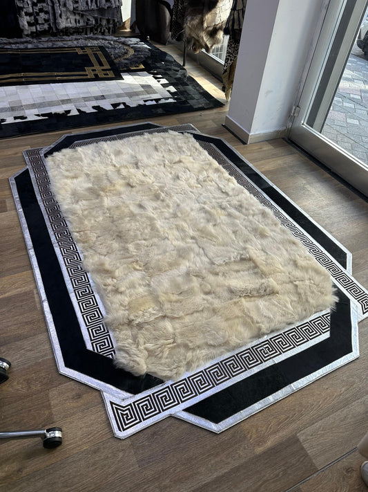 Handmade black and beige sheepskin rug with geometric border on wooden floor near window