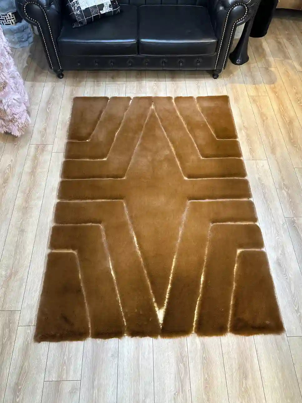 Ultra soft high-quality plush area rug in brown with geometric patterns, placed on wooden floor in living room setting