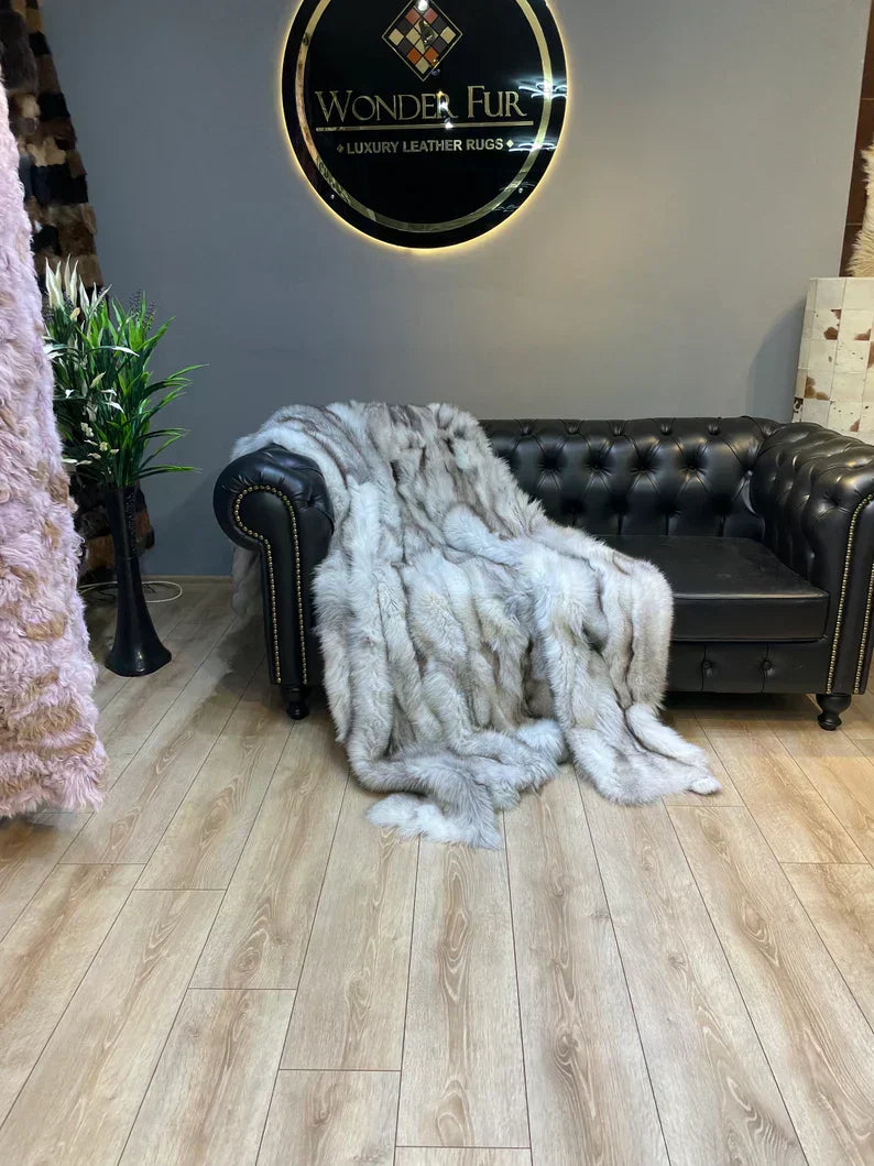 Luxury Canadian gray natural fox fur blanket draped over black leather sofa in elegant room setting