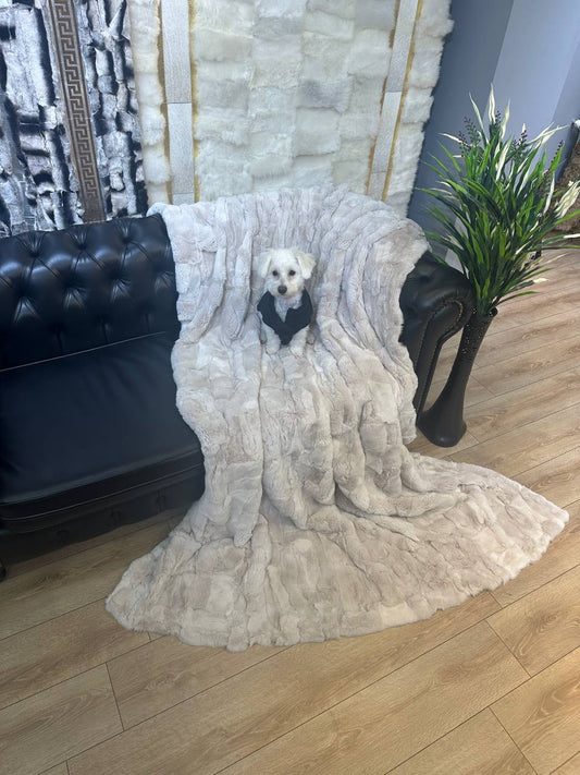 Cozy handmade real rabbit fur blanket throw draped over black sofa with small dog sitting on it in modern living room