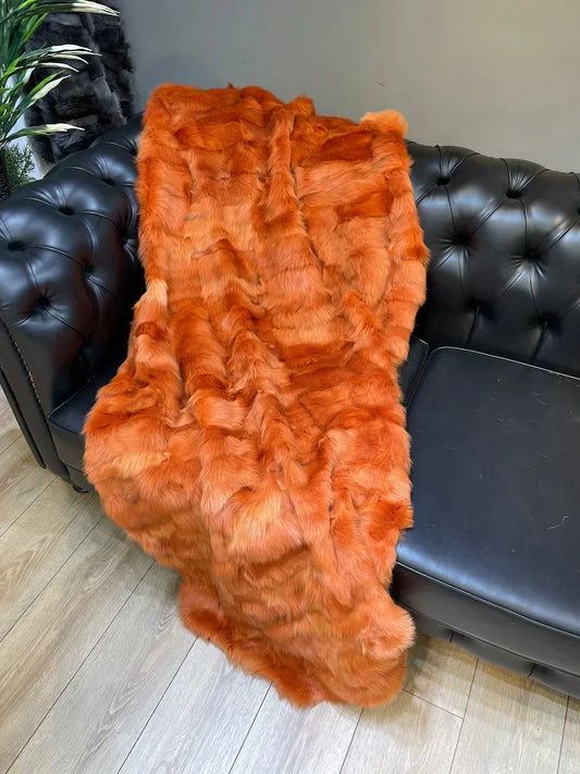 Orange sheepskin fur fluffy blanket draped on black leather sofa