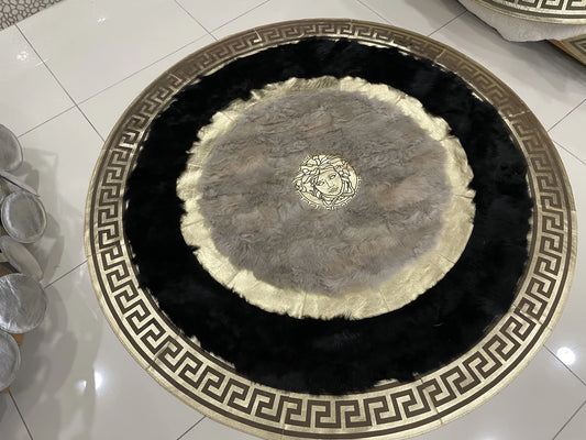 Handmade round sheepskin rug in black, white, and gold with intricate Greek key border and Medusa emblem center design