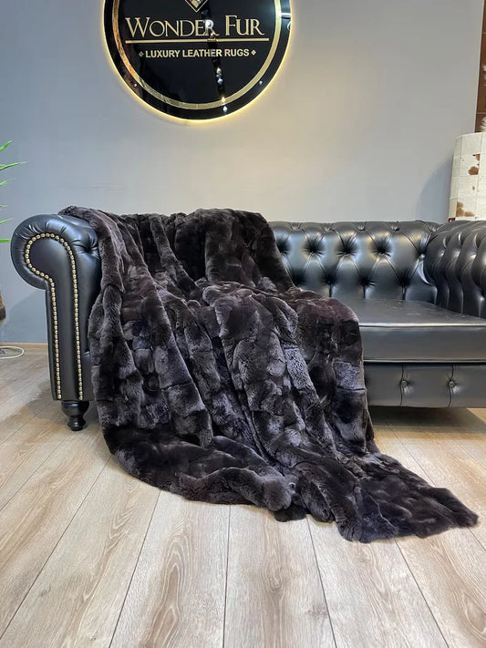 Handmade brown natural fur blanket made from Rex rabbit fur draped over black leather sofa
