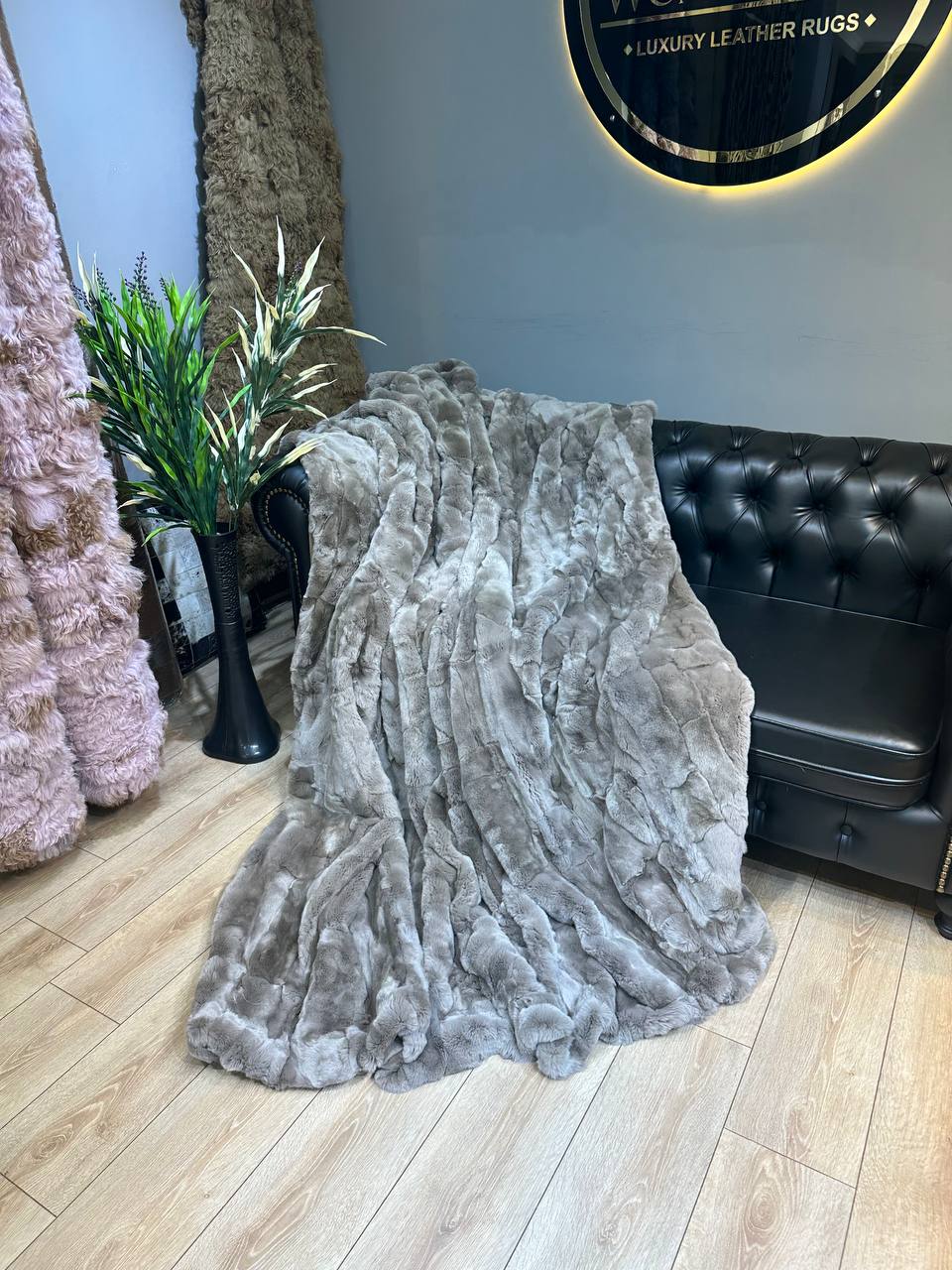 Handmade real rabbit fur blanket draped on black leather sofa in modern living room