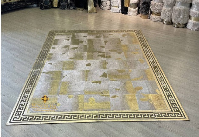 Handmade sheep leather patchwork rug with gold Greek key     border on wood flooring in a modern living room