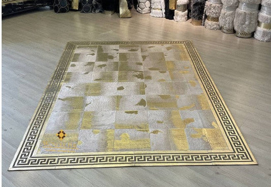 Handmade sheep leather patchwork rug with gold Greek key     border on wood flooring in a modern living room