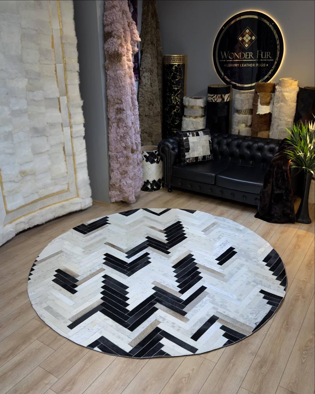 Handmade geometric round black and white cowhide patchwork rug in modern living room setting